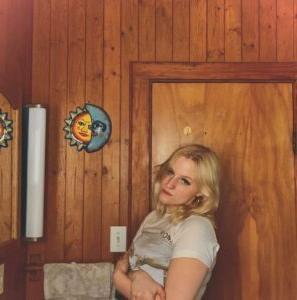 Student poet Irelyn Curry leaning against wooden door in house